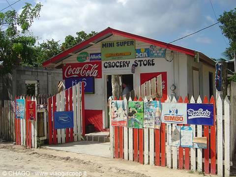 Small grocery store with Coca-Cola sign and white and red wooden fence