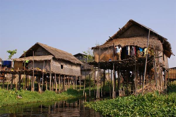 Wooden stilt houses over the water, woman hanging laundry
