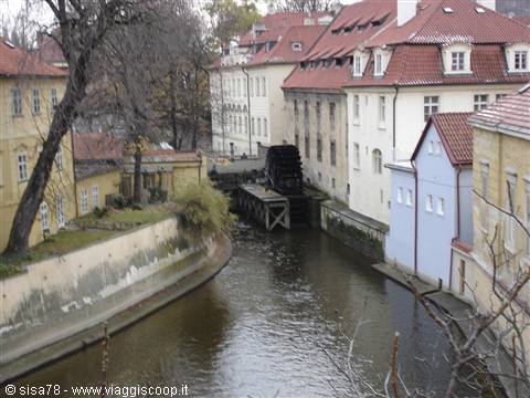Old water wheel on the Čertovka canal, colorful houses with red roofs in Prague