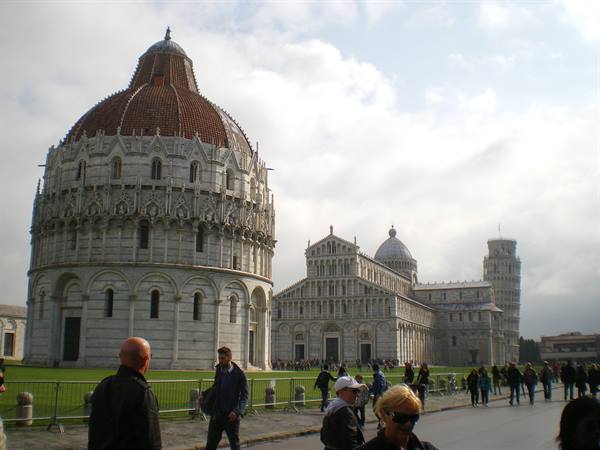 Tourists walk through Piazza dei Miracoli in Pisa, past baptistery, cathedral and leaning tower