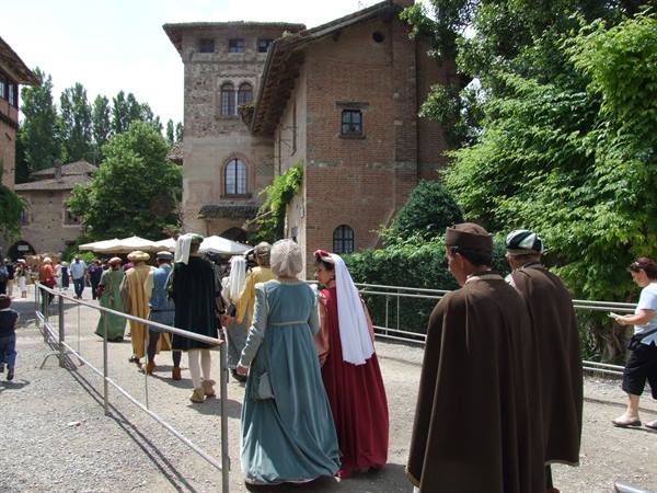 People in medieval costumes enter the Borgo Medievale in Turin among brick houses