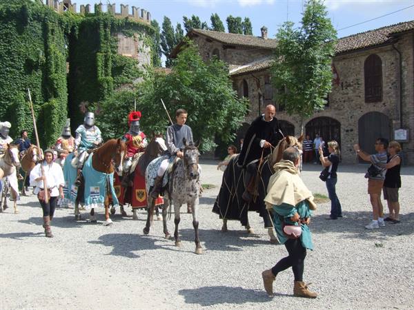 Armored knights on horseback parade before the ivy-covered castle