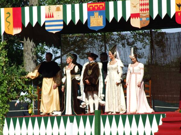 Actors in medieval costumes on stage decorated with heraldic banners