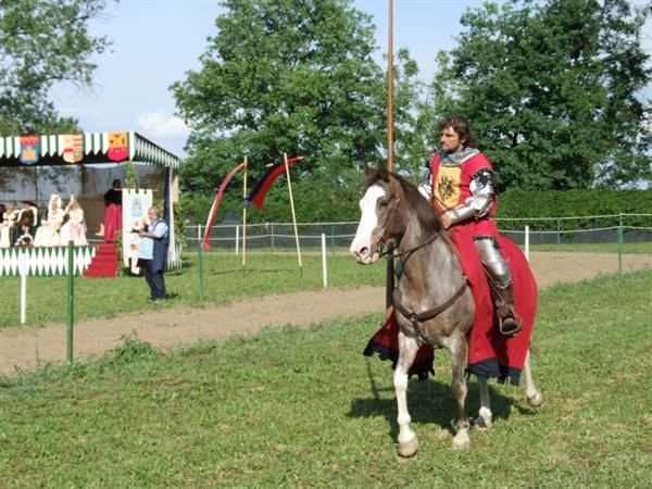 Knight in grey armor and red tunic on horseback at a medieval reenactment