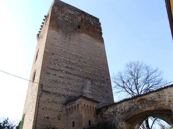 Ancient medieval brick tower against blue sky, with crenellated walls