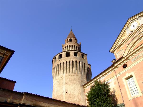 Brick tower with battlements and small dome beside a pink facade in Vigevano