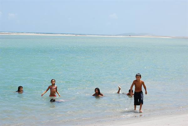 Children playing in turquoise water, white sand beach, bright light