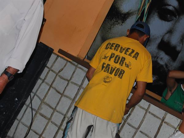 Man in blue cap and yellow "Cerveza por favor" shirt at the counter