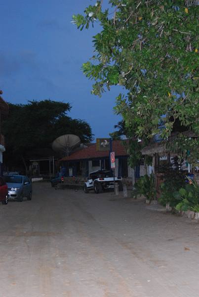 Sandy street at dusk, buggy parked near houses with tile roofs