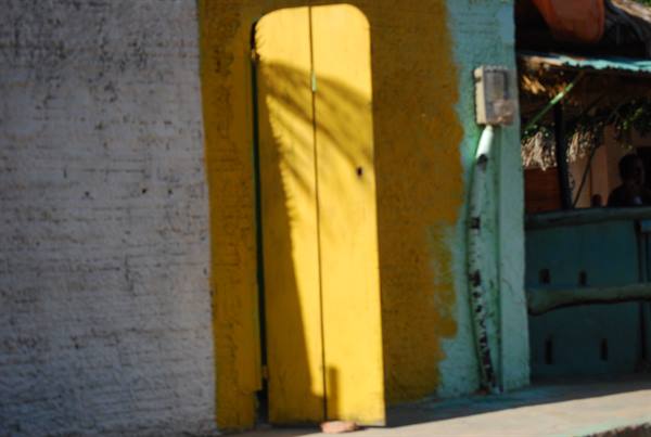 Yellow door in sunlight on white and green plastered wall