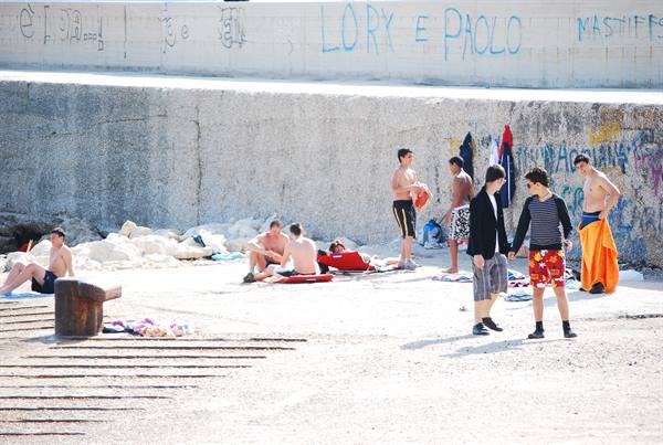 Boys in swimwear under a graffiti concrete wall by the sea