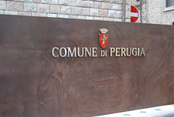 Metal sign of the Comune di Perugia with crest, on a stone wall