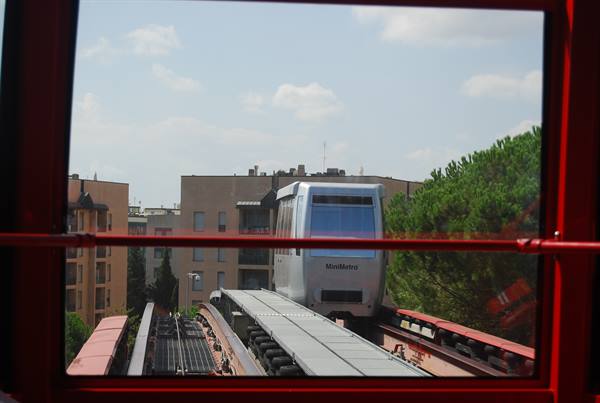 Perugia MiniMetro monorail train seen through the window, buildings and pines behind