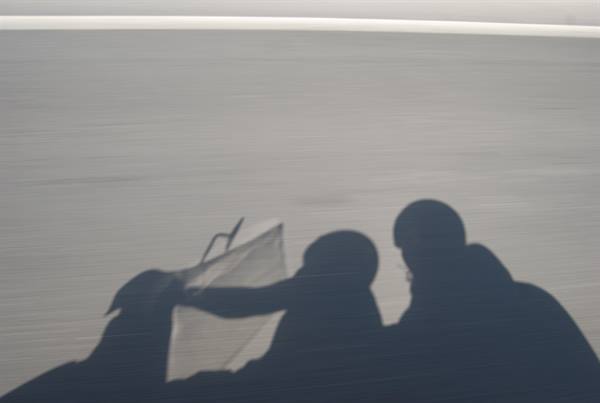Shadows of two people on a motorcycle cast on the moving asphalt