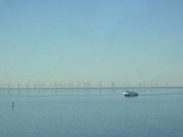 White ferry sailing past an offshore wind farm on calm sea
