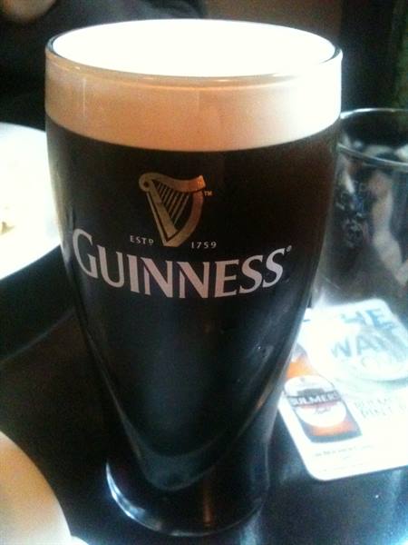 Dark Guinness pint with white foam on a pub table