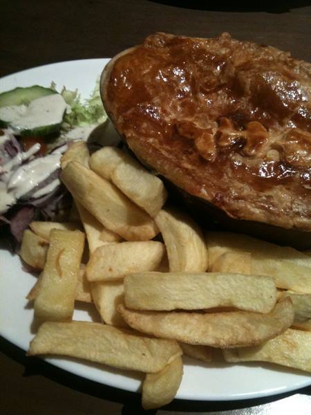 Plate of fish and chips with salad in a pub, warm light