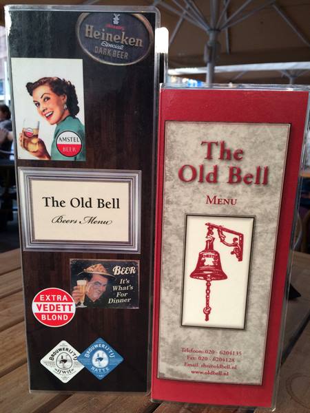 The Old Bell beer menu on wooden table with Amstel and Heineken signs