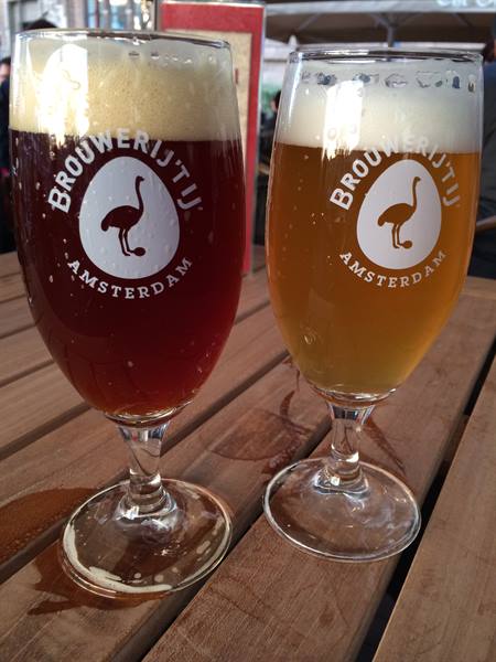 Two Brouwerij 't IJ beer glasses on a wooden table