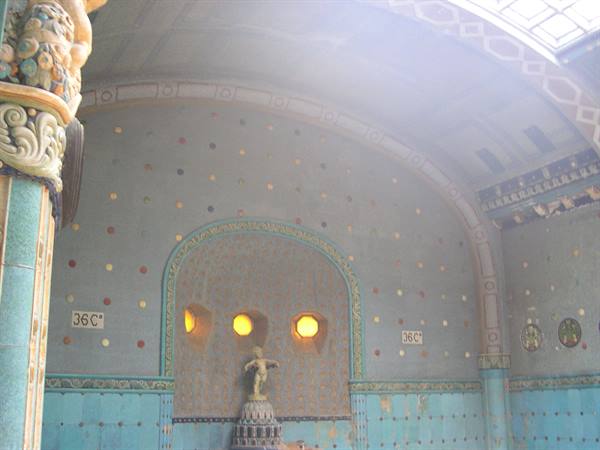 Historic bathhall with turquoise tiles, three warm lights and small statue