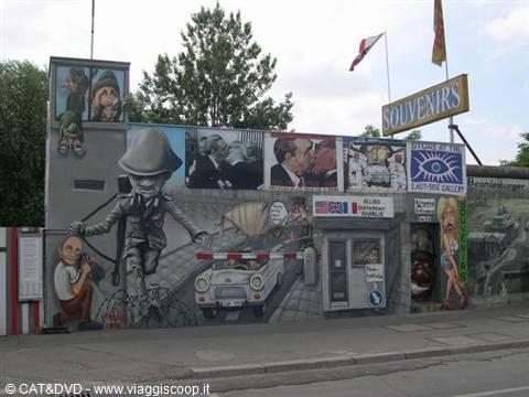 Mural paintings at Checkpoint Charlie in Berlin with souvenir sign