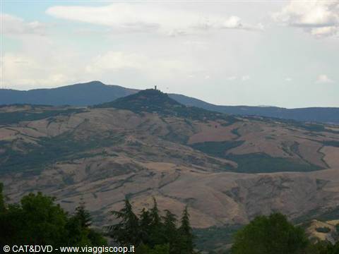 Cultivated hills with a hilltop village under cloudy sky