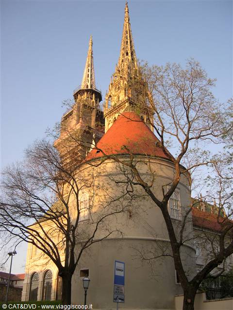 Gothic spires of Zagreb Cathedral behind a white building, golden light