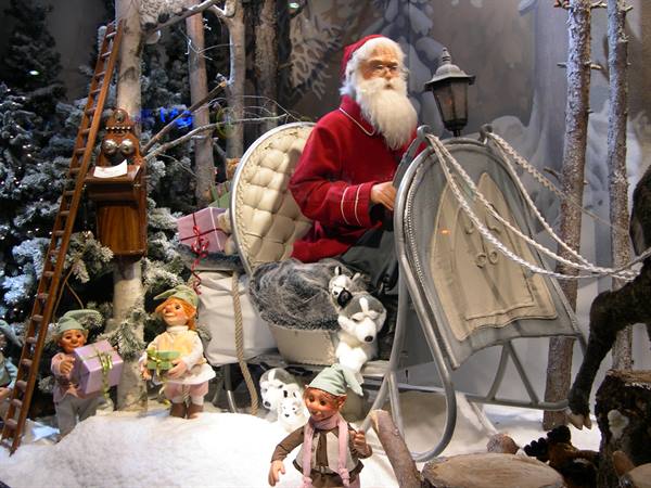 Santa Claus on a sleigh with elves and gifts among snowy trees