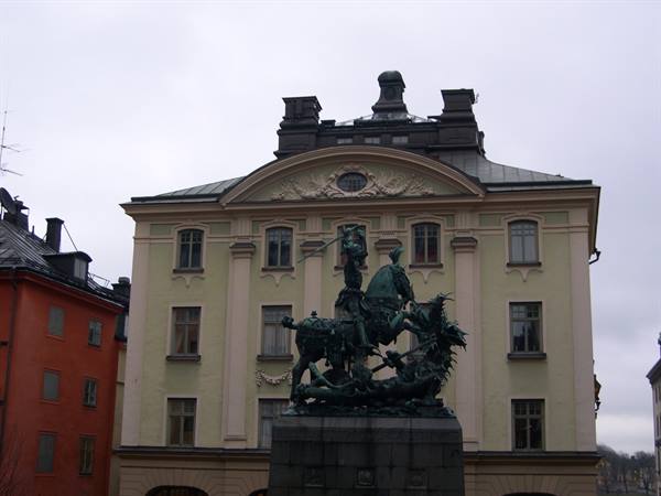 Bronze Saint George and Dragon statue before yellow building, Stockholm