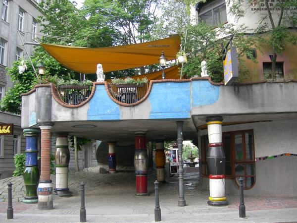 Hundertwasserhaus in Vienna, colorful ceramic columns beneath a terrace with orange canopy