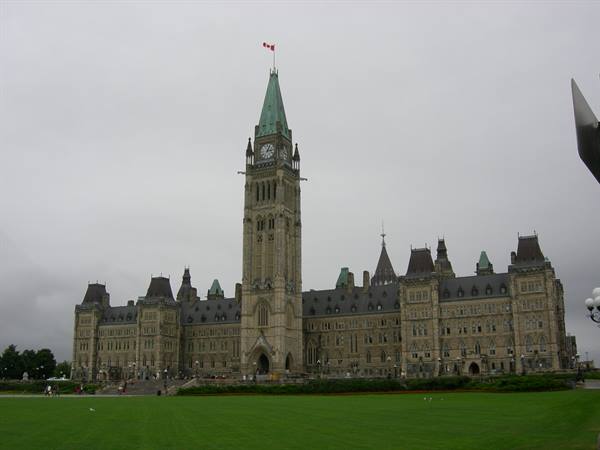 Peace Tower with Canadian flag atop Parliament Hill in Ottawa under grey sky