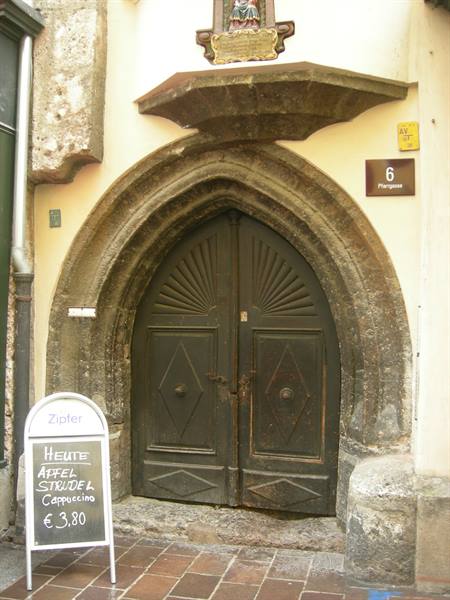 Dark wooden door under a stone Gothic arch, apple strudel sign