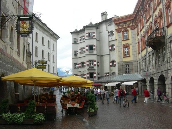 Pedestrian square in Innsbruck with yellow umbrellas and painted townhouses