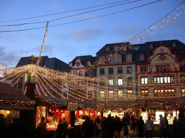 Christmas market with lit stalls and colorful historic buildings at dusk
