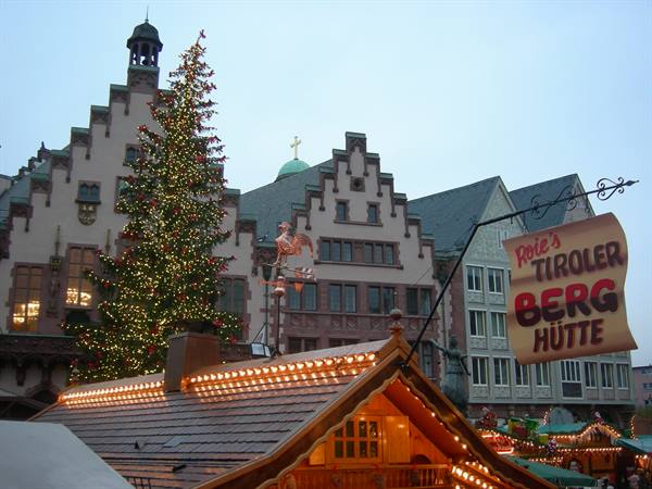 Christmas market on Römerberg in Frankfurt, lit tree and wooden chalet at dusk