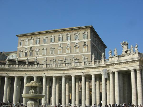 St. Peter's Square colonnade and statues, Apostolic Palace, blue sky, tourists visiting