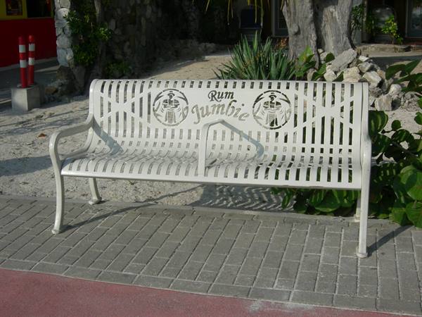 White metal bench with Rum Jumbie lettering on a brick walkway