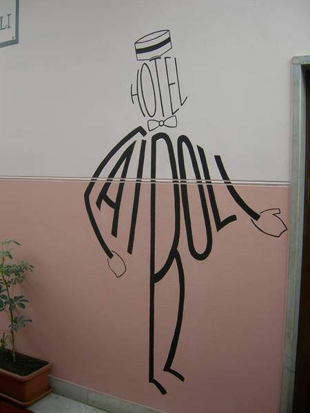 Mural of a bellhop drawn with letters on the hotel Ai Rodoli pink wall