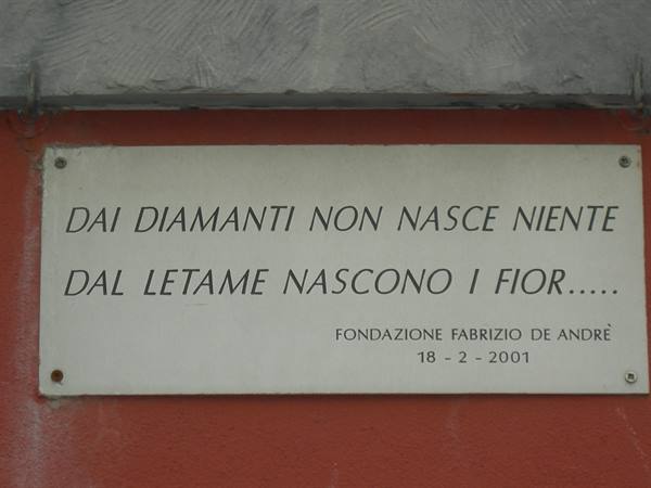 Marble plaque of Fondazione Fabrizio De André on a red wall