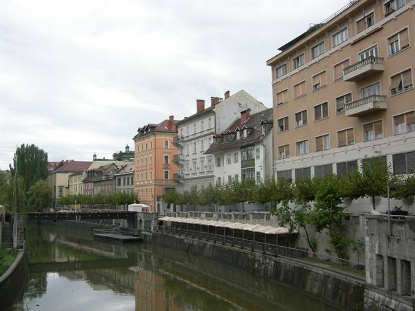 Ljubljanica river with colorful buildings and riverside umbrellas in Ljubljana