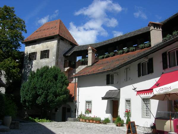 Bled Castle courtyard, stone tower, red-tiled roofs, café under awning
