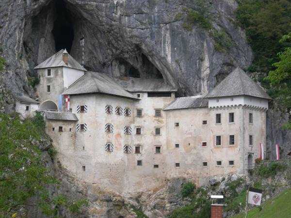 Predjama Castle built into a cliff face, pale facade and grey roofs