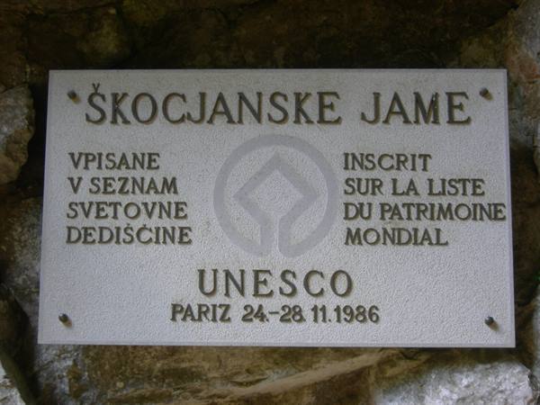 UNESCO stone plaque at Škocjan Caves, dark rock wall behind