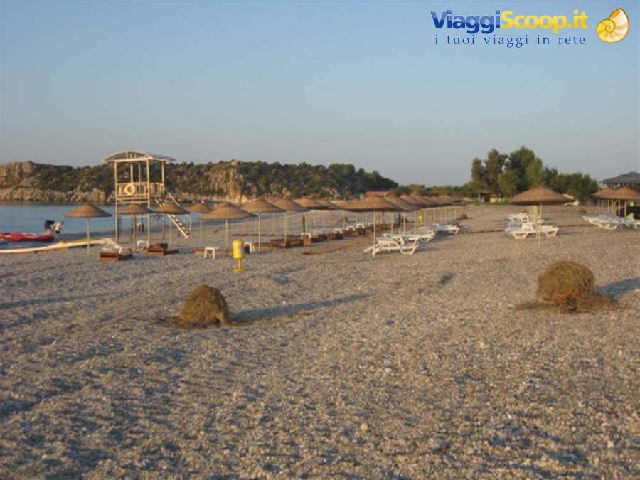 Pebble beach with straw umbrellas, empty sunbeds and wooden lifeguard tower