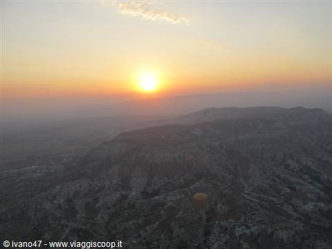 Sun rising over Göreme's rocky valleys, hot air balloon flying