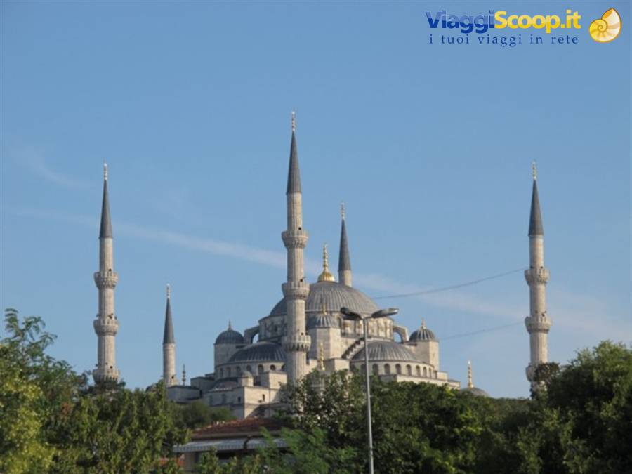 The Blue Mosque in Istanbul rises among trees under a blue sky