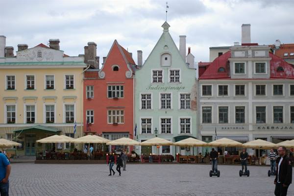 Tallinn Town Hall Square: colorful guild houses, café umbrellas and tourists on segways