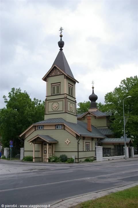 Green wooden Orthodox church with black onion dome and golden cross