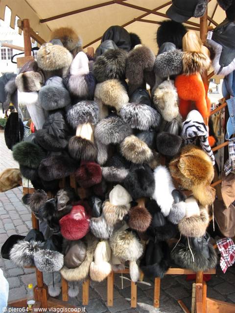 Colorful fur hats hanging under a market tent in daylight