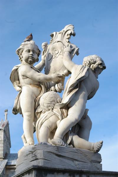 Marble putti statues holding OPA crest, pigeon perched, Pisa cathedral